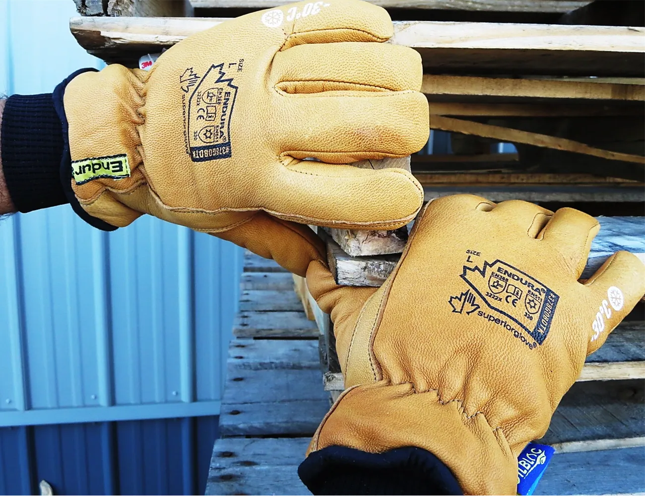 Hands wearing tan Endura 378GOBDTK winter gloves handling wooden pallets in cold weather conditions.